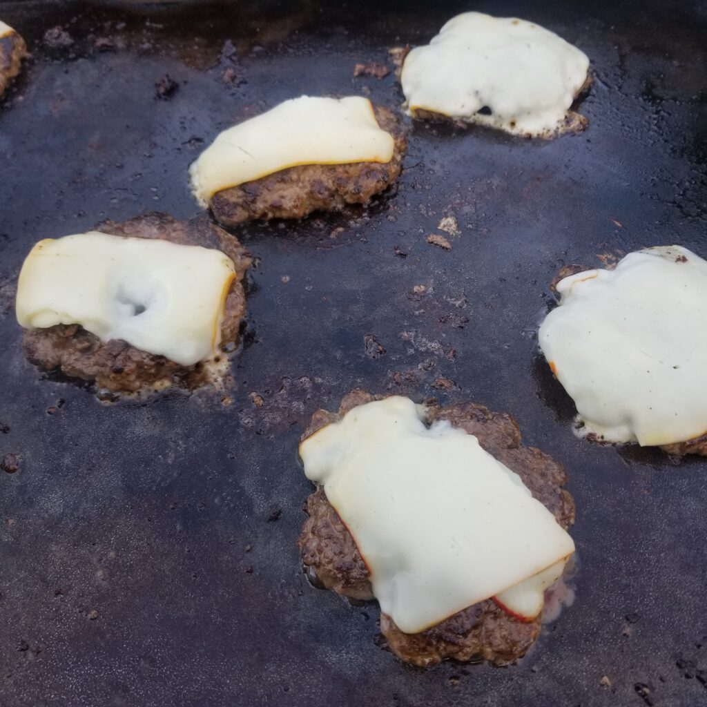 Homemade cheeseburgers on the griddle.